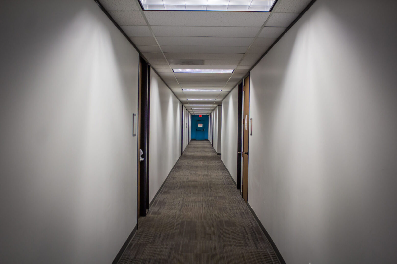 An empty hallway with a blue door at the end